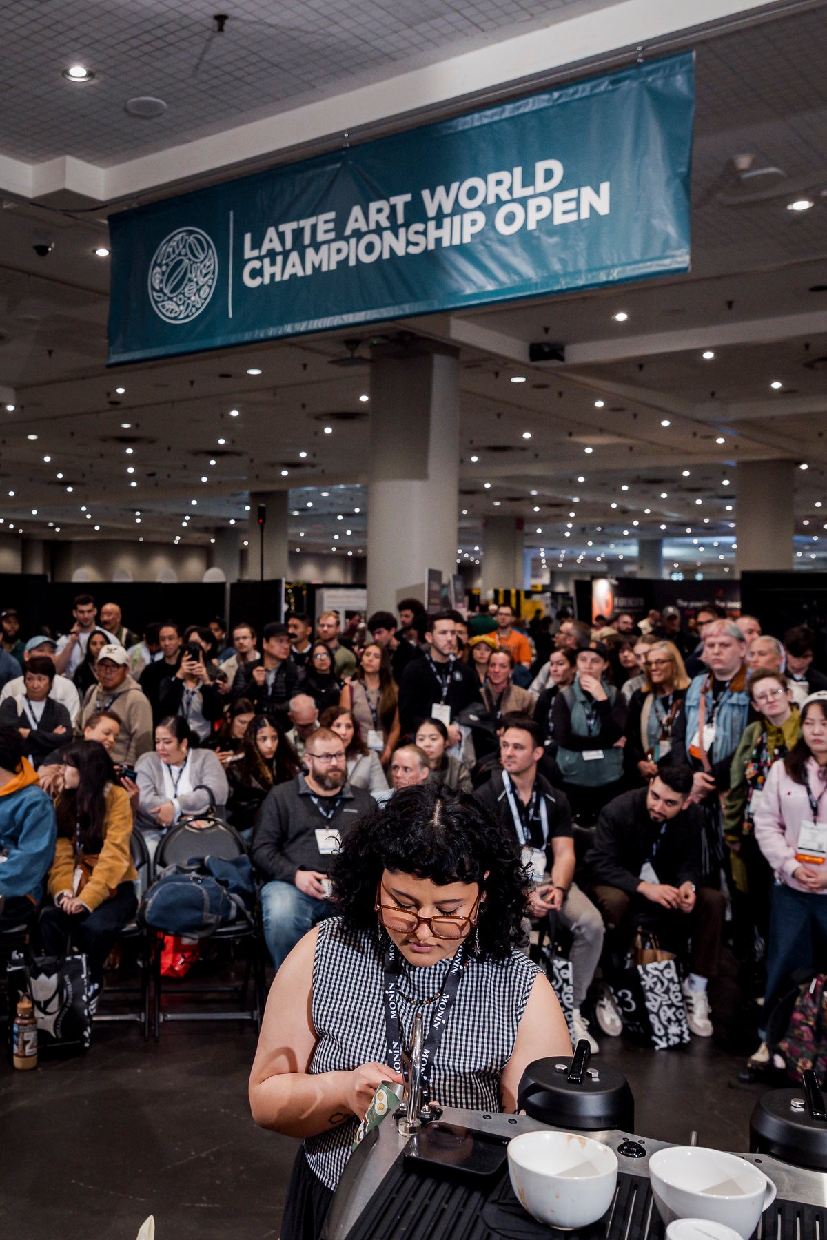 Competitor pours in front of a full crowd at the Latte Art World Championship Open, Coffee Fest New York, 2026