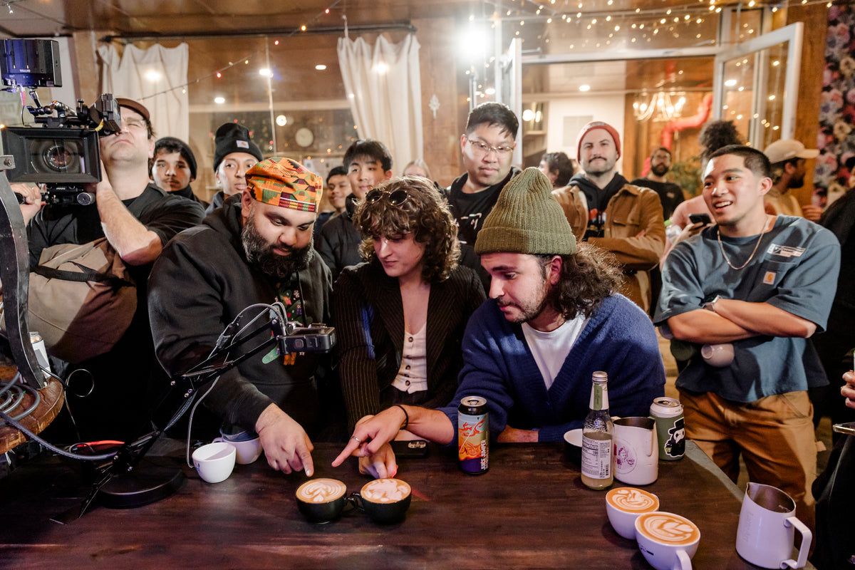 Crowd leaning in over finished latte art pours at the ESOM holiday party at Château Le Woof, 2024