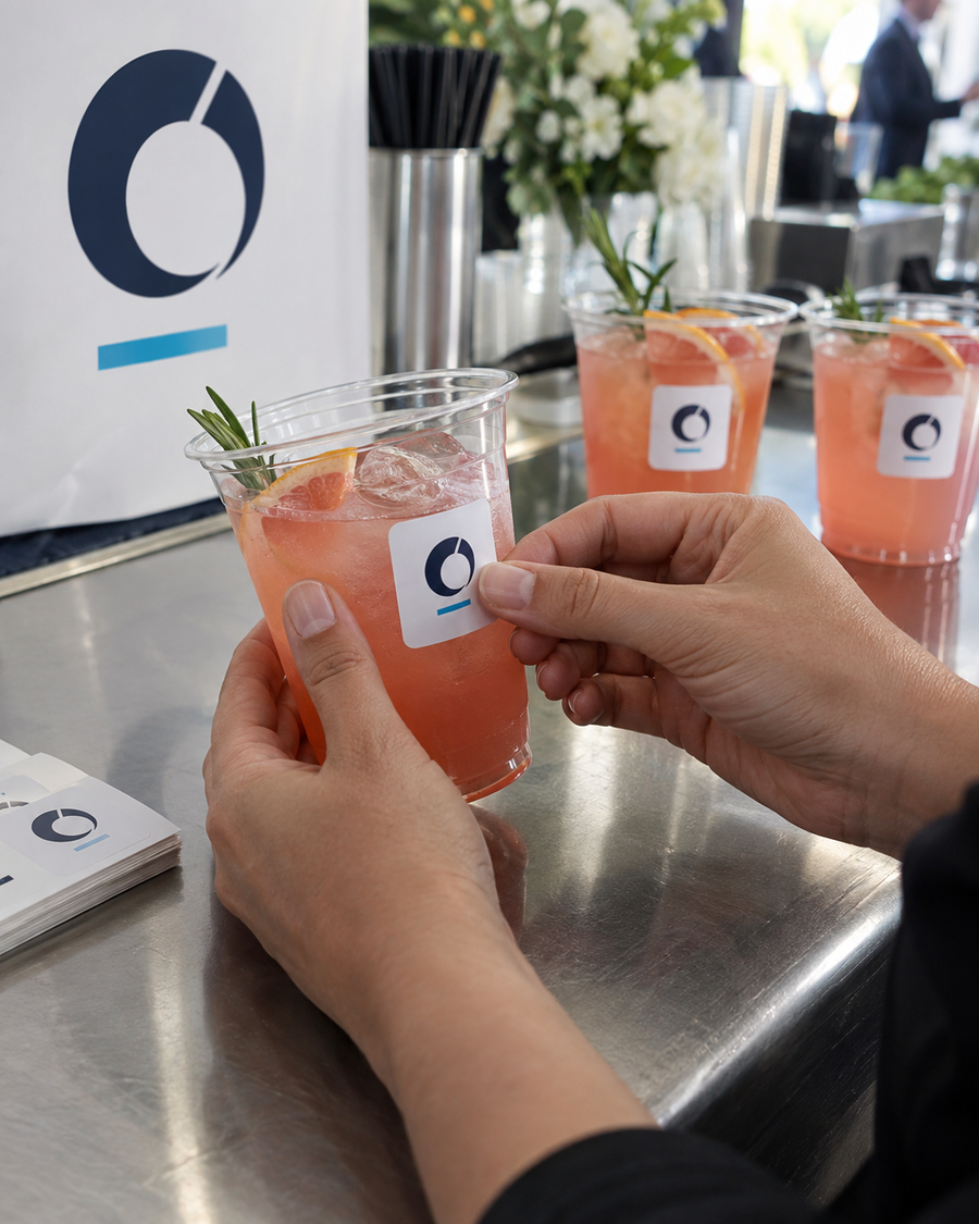Hands holding iced drinks in cups printed with a brand logo